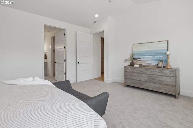 bedroom with light carpet, ensuite bathroom, and vaulted ceiling