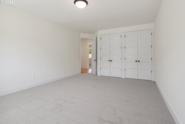 unfurnished bedroom with carpet flooring and two closets