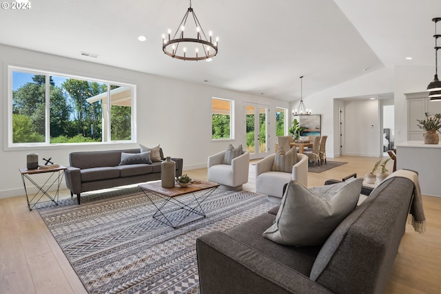 living room with light hardwood / wood-style floors, an inviting chandelier, plenty of natural light, and lofted ceiling