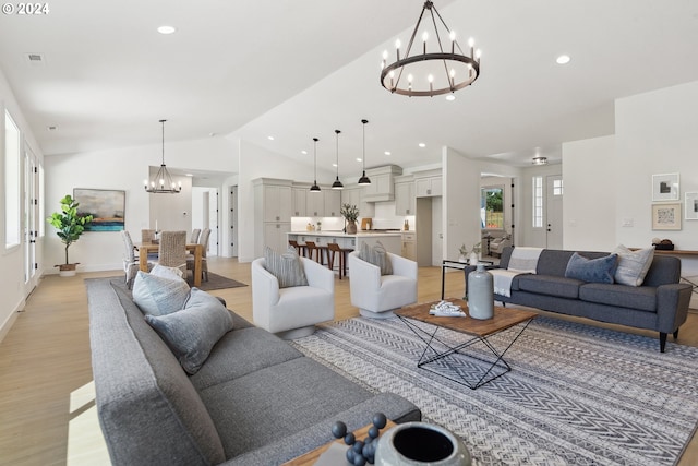 living room with light wood-type flooring, vaulted ceiling, and a notable chandelier