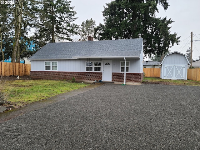 view of front facade with fence, a storage unit, an outbuilding, and brick siding