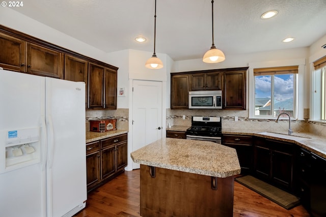 kitchen featuring hanging light fixtures, a kitchen island, stainless steel appliances, sink, and dark hardwood / wood-style floors