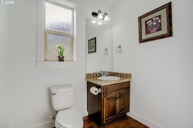 bathroom featuring toilet, vanity with extensive cabinet space, and wood-type flooring