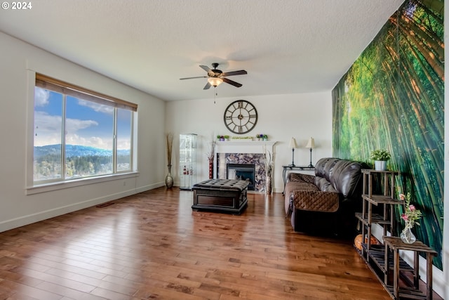 living room featuring a textured ceiling, wood-type flooring, and ceiling fan