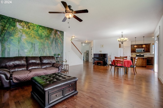 living room with dark wood-type flooring and ceiling fan with notable chandelier