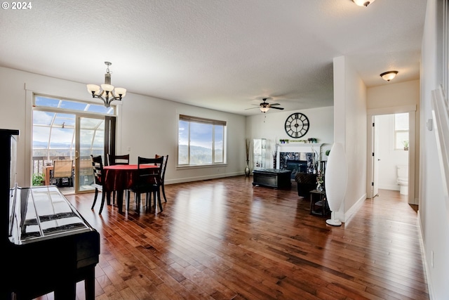 dining area featuring dark hardwood / wood-style flooring, ceiling fan with notable chandelier, and plenty of natural light