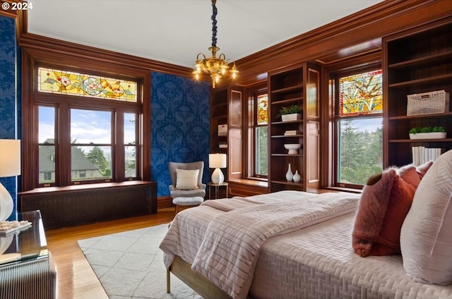 bedroom with a notable chandelier, crown molding, and light hardwood / wood-style floors