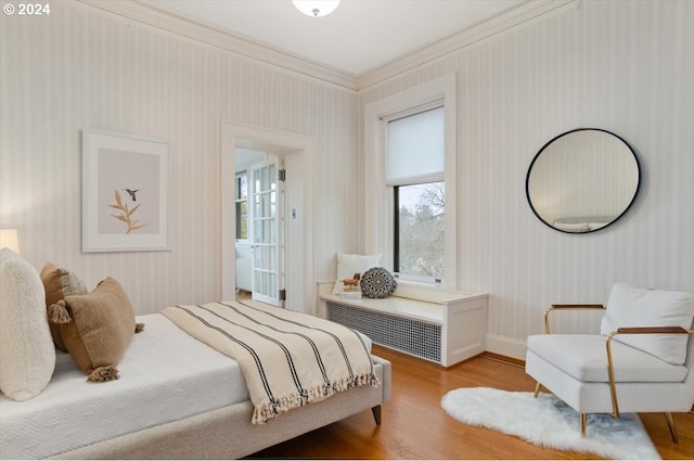 bedroom featuring baseboards, wallpapered walls, light wood-style flooring, and crown molding