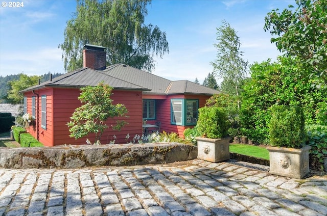 view of property exterior with a chimney and a patio