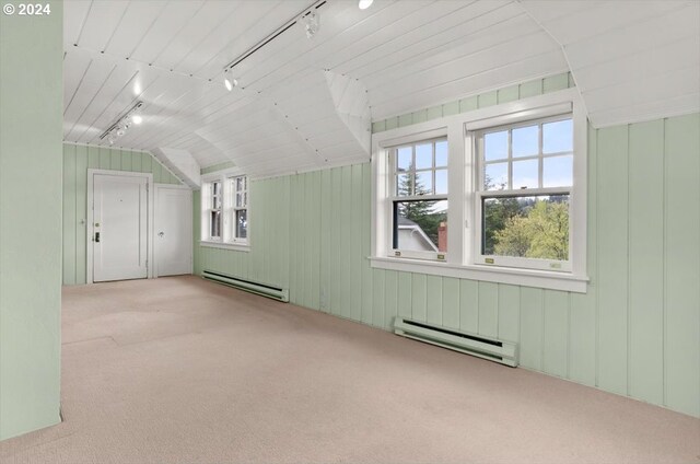 additional living space with lofted ceiling, light colored carpet, wooden walls, and baseboard heating