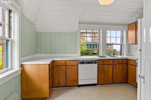 kitchen with lofted ceiling, light countertops, brown cabinetry, white dishwasher, and a sink