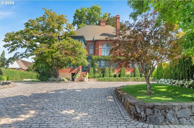 view of front of house with a front yard, brick siding, and a chimney