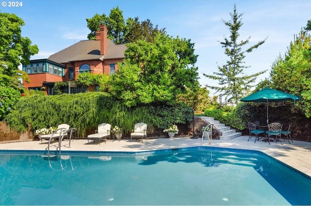 pool featuring stairs and a patio