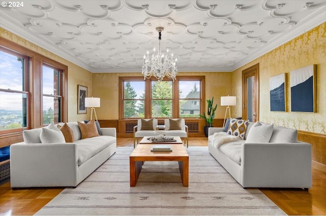 living room featuring radiator heating unit, crown molding, an inviting chandelier, and a healthy amount of sunlight