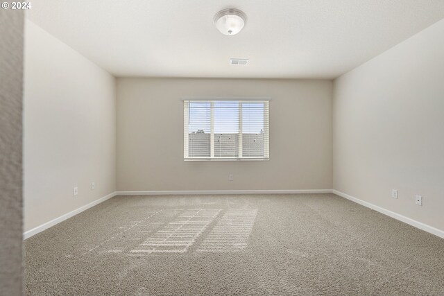 carpeted empty room featuring visible vents and baseboards