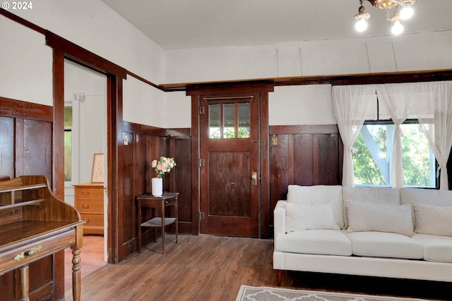 living room with wooden walls, a chandelier, and hardwood / wood-style flooring