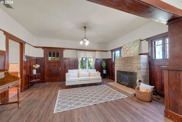 living room featuring wood-type flooring, an inviting chandelier, and wood walls