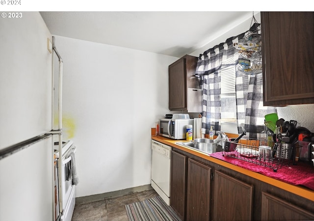 kitchen with dark brown cabinetry, white appliances, and sink