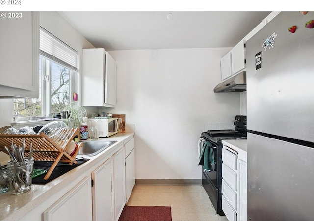 kitchen featuring black electric range, stainless steel fridge, white cabinets, and sink