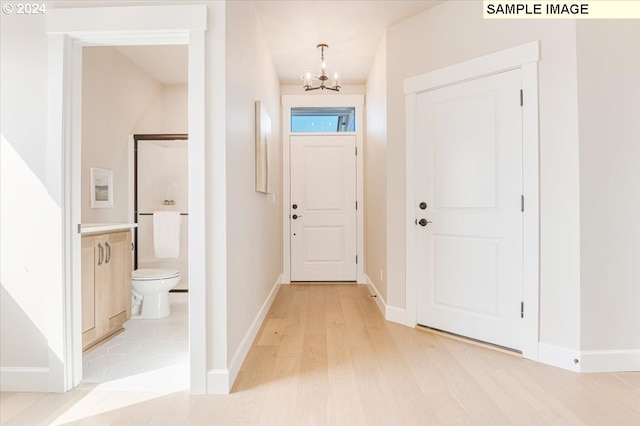 foyer entrance with light hardwood / wood-style flooring and a chandelier