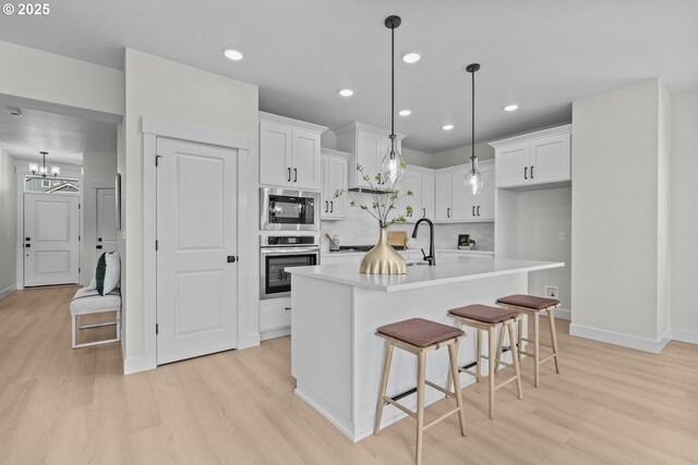 12785 SW Trask St, Beaverton, OR 97007 - kitchen featuring appliances with stainless steel finishes, light wood finished floors, baseboards, white cabinets, and recessed lighting