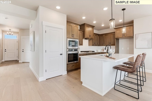 kitchen featuring sink, a center island with sink, light hardwood / wood-style flooring, and appliances with stainless steel finishes