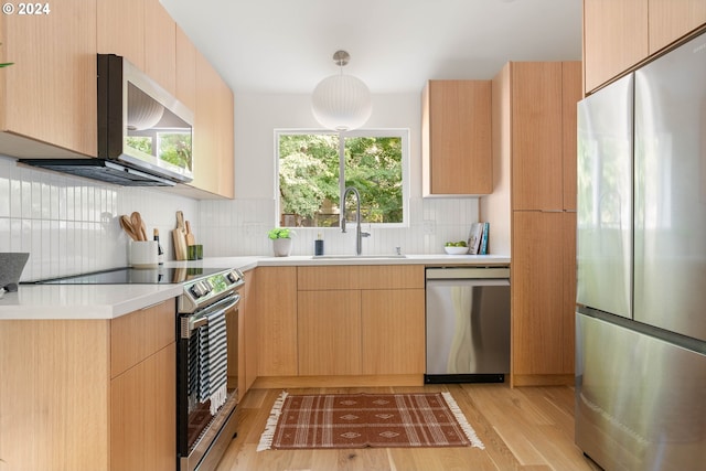 kitchen featuring appliances with stainless steel finishes, light brown cabinetry, plenty of natural light, and pendant lighting