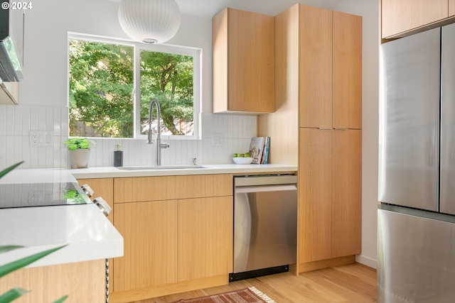 kitchen featuring decorative backsplash, stainless steel appliances, sink, light brown cabinetry, and light hardwood / wood-style floors