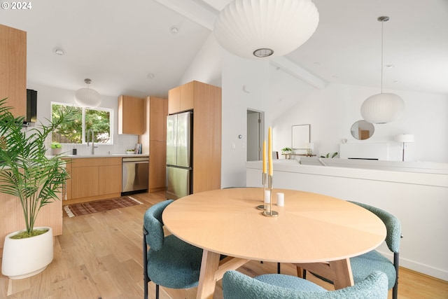 dining room featuring lofted ceiling with beams, sink, and light wood-type flooring