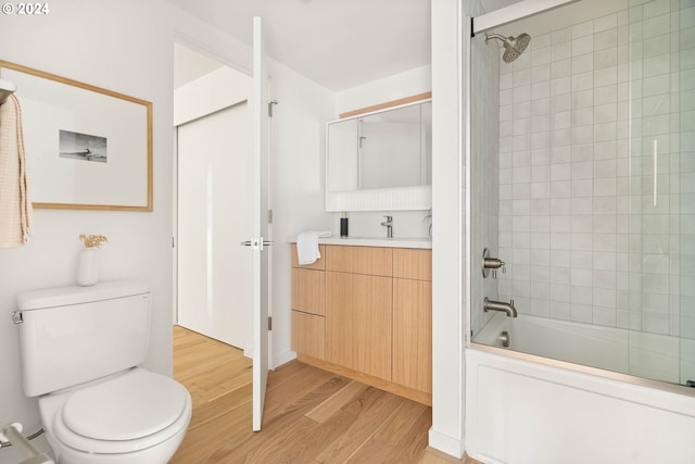 full bathroom with tiled shower / bath, vanity, wood-type flooring, and toilet