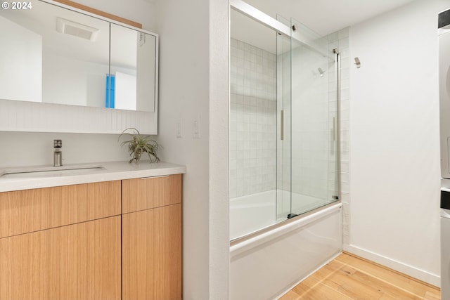 bathroom with vanity, wood-type flooring, and shower / bath combination with glass door