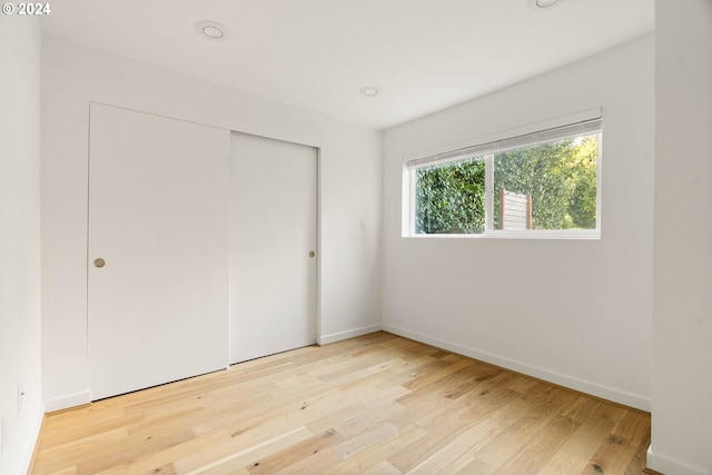 unfurnished bedroom with a closet and light wood-type flooring