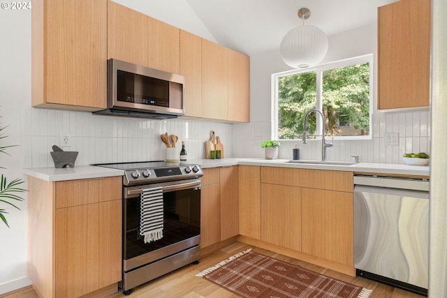 kitchen with sink, appliances with stainless steel finishes, light wood-type flooring, and light brown cabinets