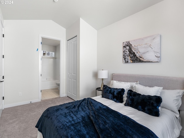 bedroom featuring light carpet, connected bathroom, a closet, and lofted ceiling