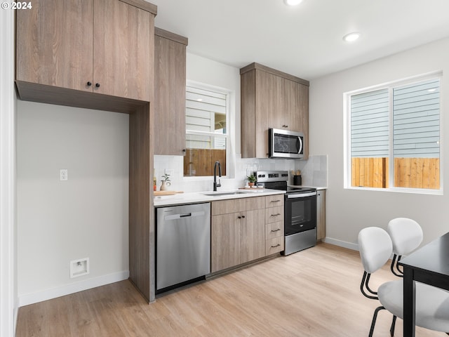 kitchen featuring decorative backsplash, stainless steel appliances, light hardwood / wood-style flooring, and sink