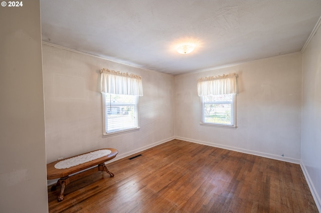 unfurnished room featuring wood-type flooring, ornamental molding, and plenty of natural light