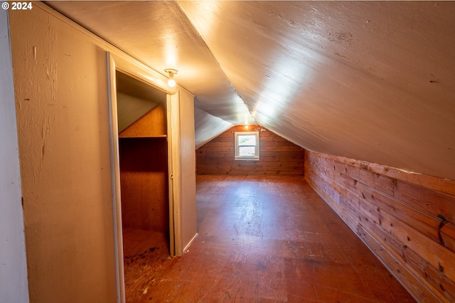 additional living space with wood-type flooring, vaulted ceiling, and wooden walls