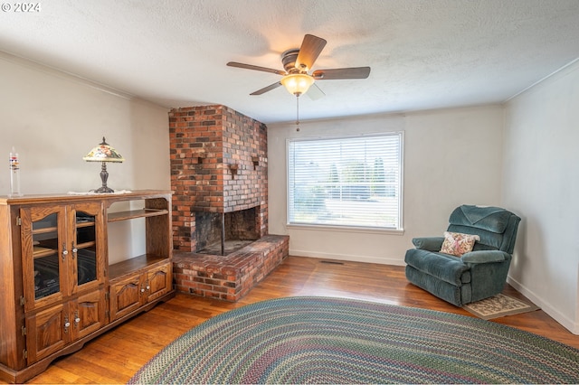 living room featuring ceiling fan, hardwood / wood-style flooring, crown molding, and a textured ceiling