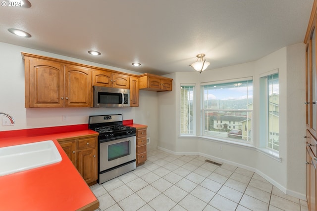 kitchen featuring light tile patterned floors, stainless steel appliances, plenty of natural light, and sink