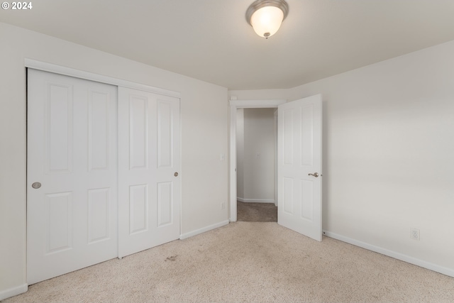 unfurnished bedroom featuring light carpet and a closet