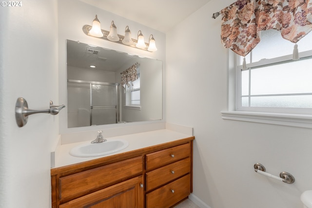 bathroom featuring vanity, a shower with shower door, and a wealth of natural light