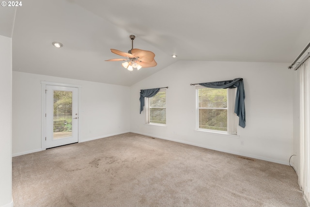 carpeted empty room with a wealth of natural light, ceiling fan, and lofted ceiling