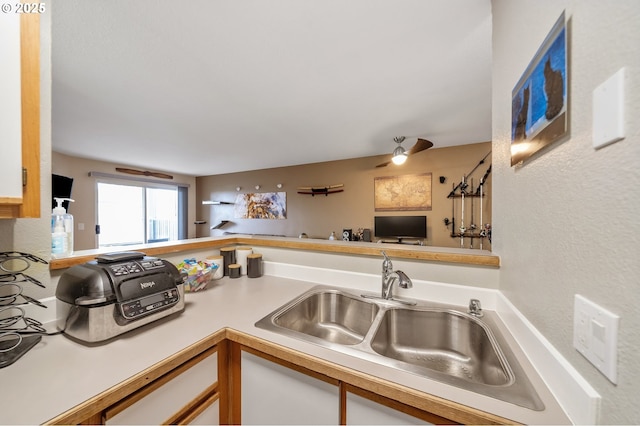 kitchen with white cabinets, ceiling fan, kitchen peninsula, and sink