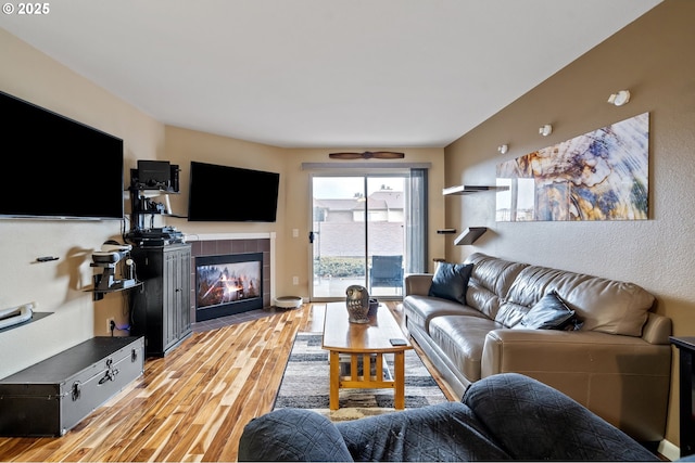 living room with a tile fireplace and light wood-type flooring