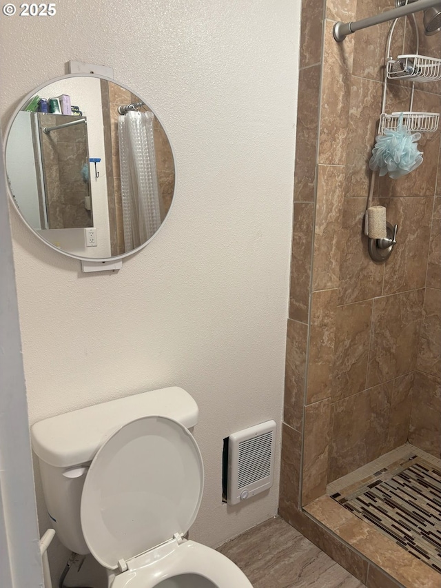 bathroom featuring toilet, heating unit, a shower stall, and wood finished floors