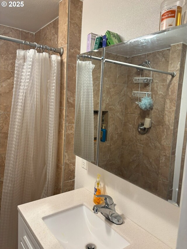 bathroom with tiled shower and vanity