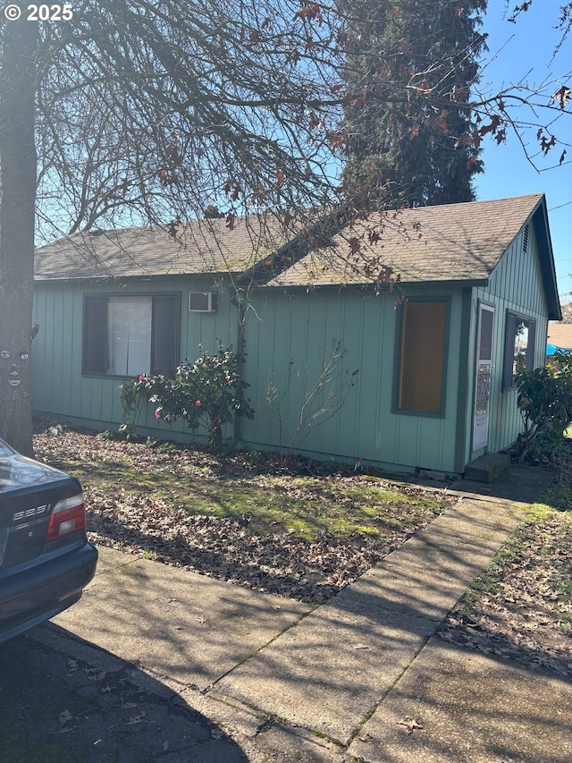 view of side of property with board and batten siding and roof with shingles