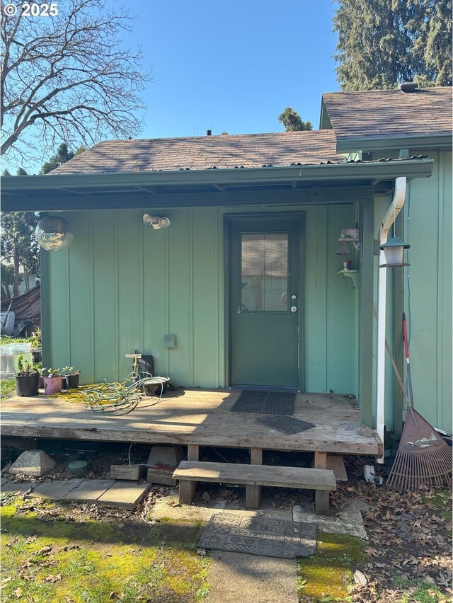 view of exterior entry featuring a shingled roof