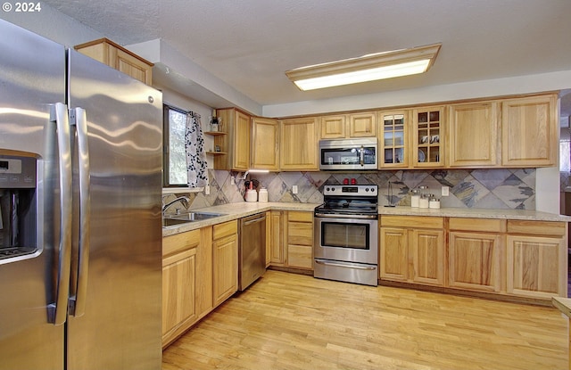 kitchen featuring backsplash, stainless steel appliances, sink, and light hardwood / wood-style floors