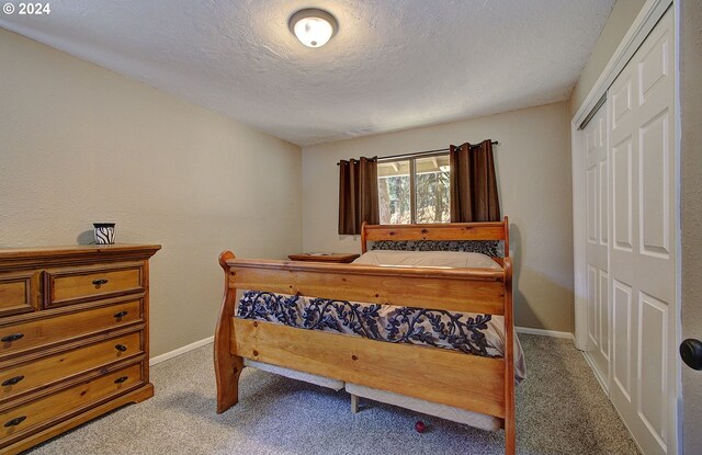 carpeted bedroom with a textured ceiling and a closet